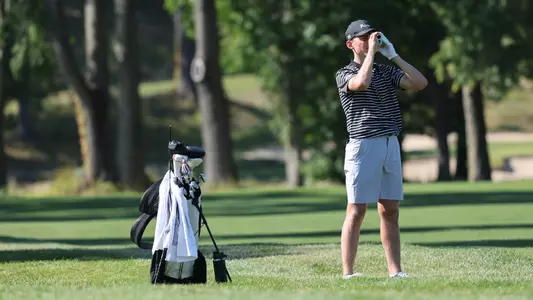 Men's golf player Liam O'Grady using his range finder on the course