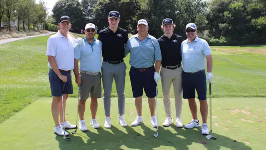 Men's hockey players Tomas Machu and Kale McCallum pose with participants at the annual men's hockey vision cup golf tournament.