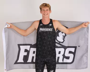 Tucker Anglemyer holding a Friar flag behind her back 