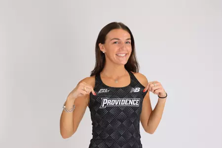 Women's track athlete Polly Bogdan poses holding jersey in uniform for media day