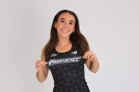Women's track athlete Emily Bush poses holding jersey for media day