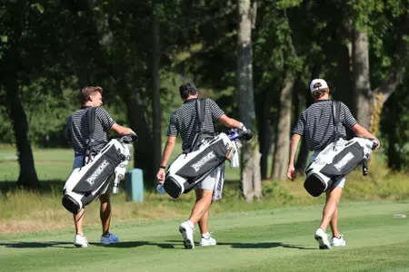 Men's golf players Joe Halferty, Callan Fahey and Will Spring walking up the fairway with their golf bags