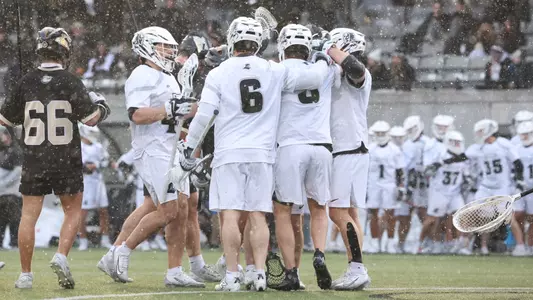 Lacrosse team celebrates a goal in a light snow fall game versus Bryant on Chapey Field at Anderson Stadium