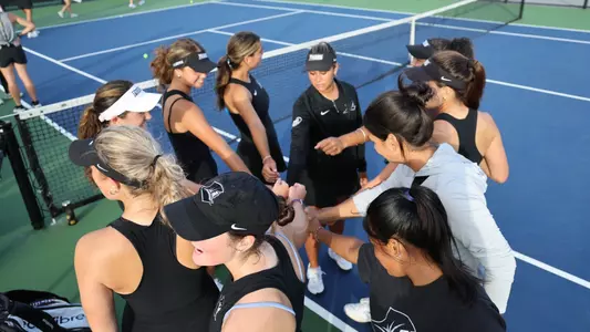 Women's Tennis huddles before a match against Assumption