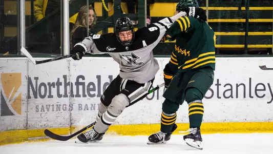 Men's Hockey's Hudson Malinoski fends off a Vermont defenseman