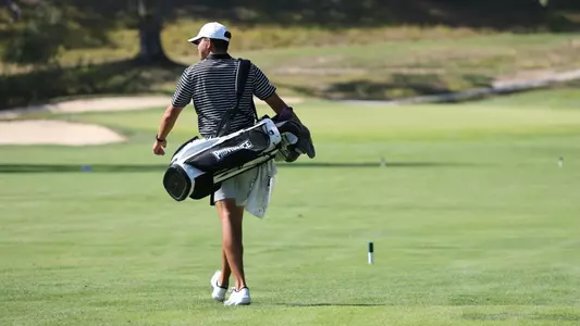 Men's golfer Campbell Skelly walking up the fairway with his bag