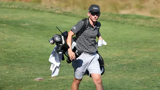 Men's golfer Liam O'Grady walking with his bag