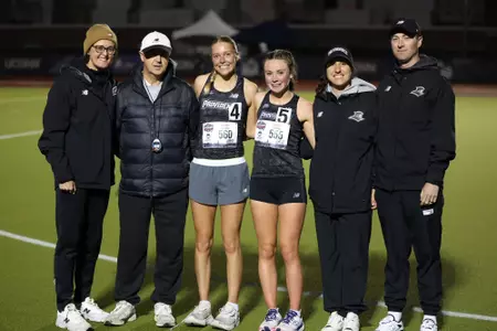 Gabby Schmidt and Niamh O'Mahony pose with the coaches following the 10K at the 2026 BIG EAST Championship
