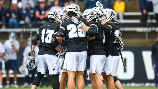 Lacrosse team huddle photo in BIG EAST Championship game wearing black jerseys and white helmets. 