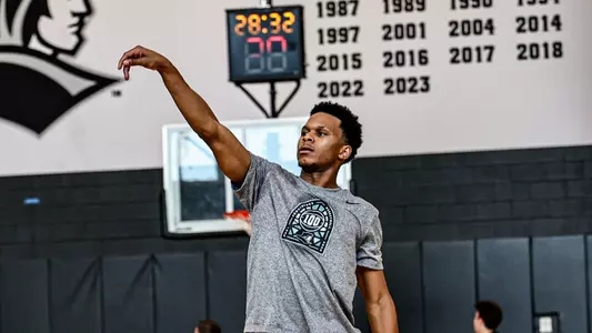 Men's basketball player Gavin Hightower following through on a shot during a practice