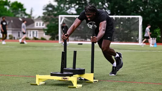Samson Aletan pushing weighted sled during a workout