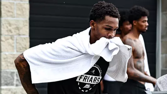 Devin Vanterpool on assault bike biting down on towel during tough workout