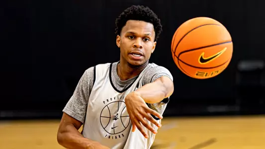 Men's basketball player Gavin Hightower passing a ball during a practice