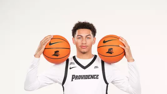 Men's basketball player Miles Byrd posing with two basketballs in his hands during a photo shoot