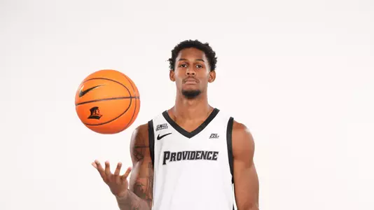Men;s basketball player Devin Vanterpool poses throwing a basketball in the air during a photo shoot
