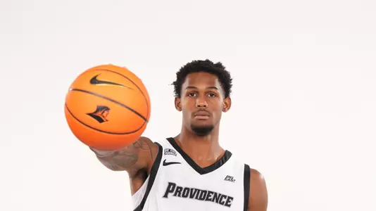 Men's basketball player Devin Vanterpool poses with a basketball in one hand during a photo shoot