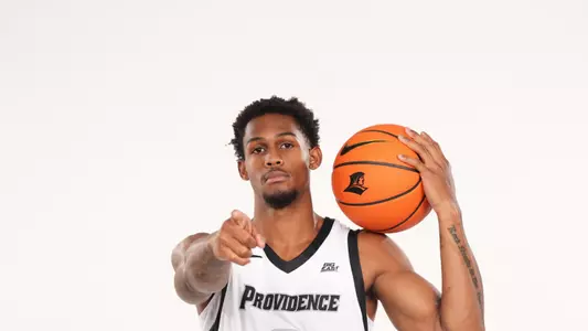 Men's basketball player Devin Vanterpool poses with a basketball in his hand and pointing at the camera