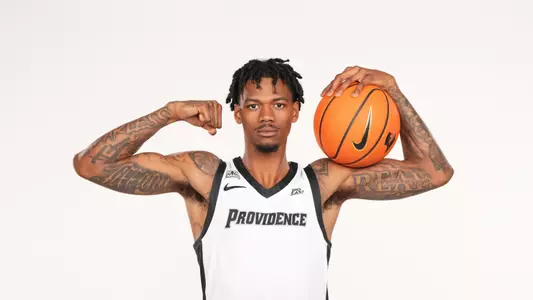 Men's basketball player Dink Pate poses for a picture flexing with a basketball in his hand during a photo shoot