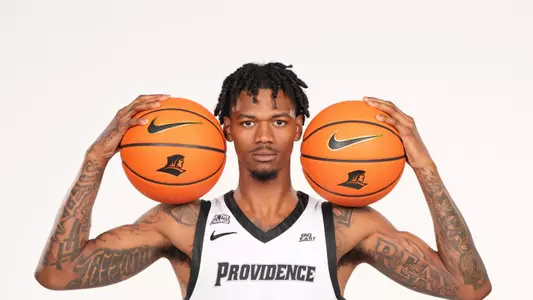 Men's basketball player Dink Pate poses with two basketballs in his hands during a photo shoot