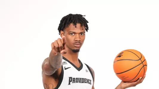 Men's basketball player Dink Pate poses with a basketball in his hand and pointing at the camera during a photo shoot