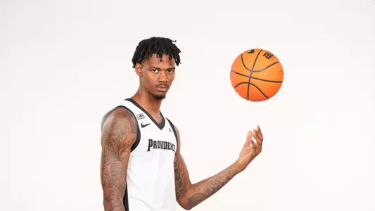 Men's basketball player Dink Pate poses throwing a basketball into the air during a photo shoot