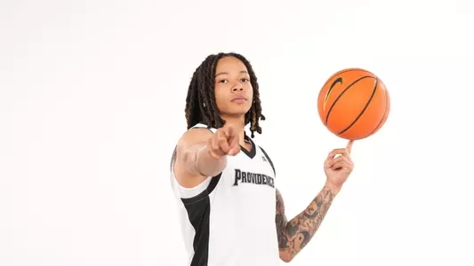 Men's basketball player Malik Mack poses spinning a basketball on his finger and points at the camera during a photo shoot