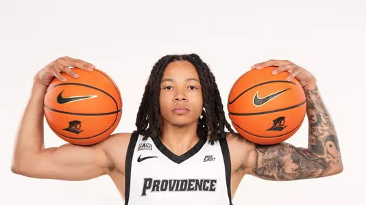 Men's basketball player Malik Mack poses with two basketballs on his shoulders during a photo shoot