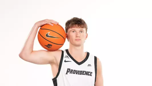 Men's basketball player Ryan Sabol poses with a basketball on his shoulder during a photo shoot