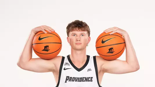 Men's basketball player Ryan Sabol poses with two basketballs on his shoulders during a photo shoot
