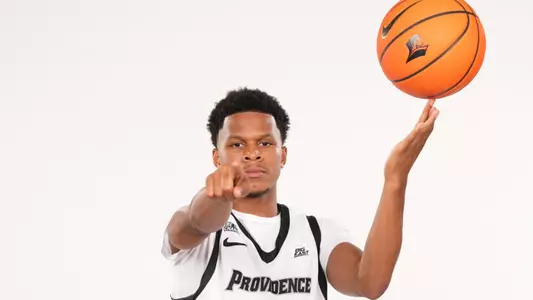 Men's basketball player Gavin Hightower spinning a basketball on his finger and pointing at the camera