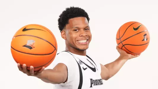 Men's basketball player Gavin Hightower posing with two basketballs during a photoshoot