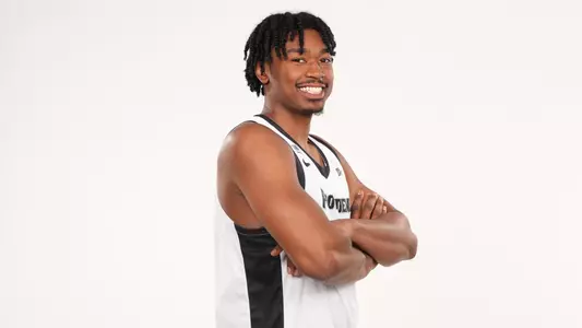 Men's basketball player Jacob Bannarbie posing with his arms folder for a photo