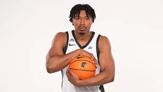 Men's basketball player Jacob Bannarbie posing with a basketball for a photo