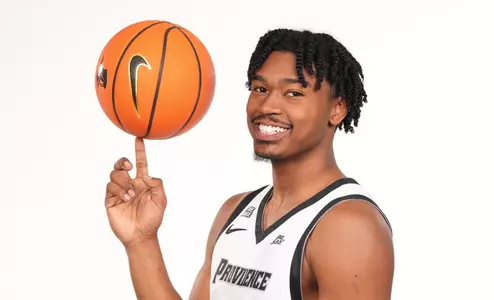 Men's basketball player Jacob Bannarbie spinning a basketball on his finger while posing for a photo