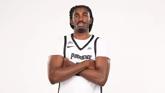 Men's basketball player Samson Aletan posing for a photo with his arms crossed