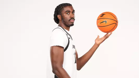 Men's basketball player Samson Aletan throwing a basketball up during a photoshoot