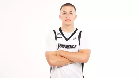 Men's basketball player John Jackson posing for a photo with his arms crossed