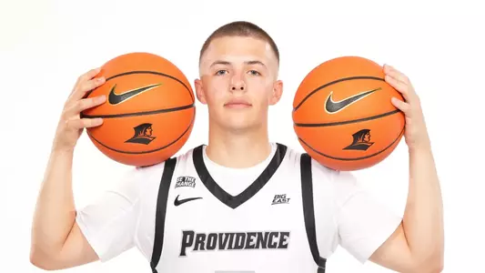 Men's basketball player John Jackson posing with a basketball on each shoulder
