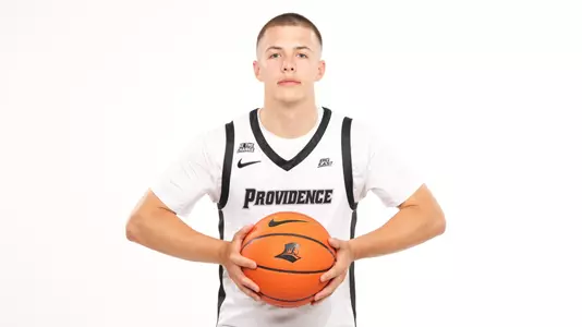Men's basketball player John Jackson posing with a basketball