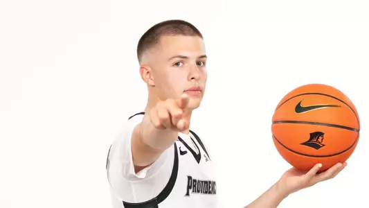 Men's basketball player John Jackson pointing at the camera while holding a basketball