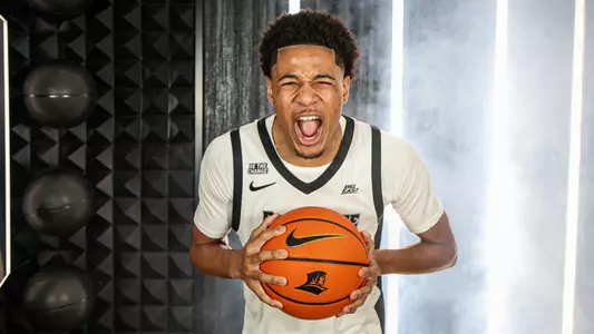 Men's basketball player Clyde Walters screaming into the camera holding a basketball