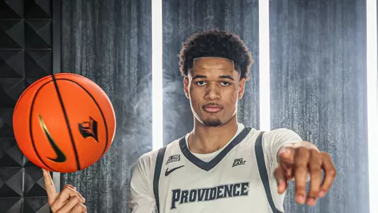 Men's basketball player Clyde Walters spinning a basketball on his finger and pointing at the camera