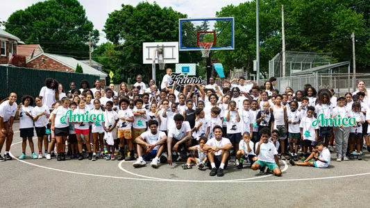 A group picture with the men's and women's basketball teams and the Providence Recreation Department Summer Program during a summer clinic