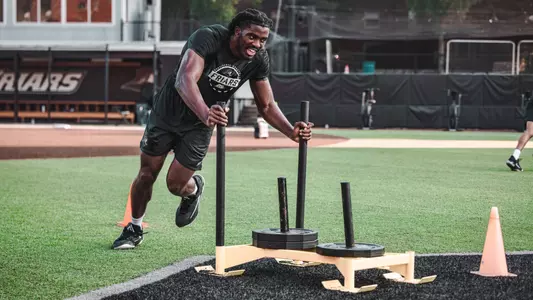Men's Basketball player Samson Aletan pushing the sled during practice 