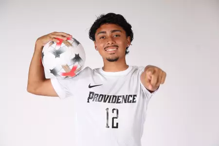 Luis Gutierrez holding ball on his shoulder while pointing at the camera 