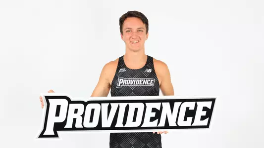 Adam Wedlake holding a Providence sign during a photo shoot