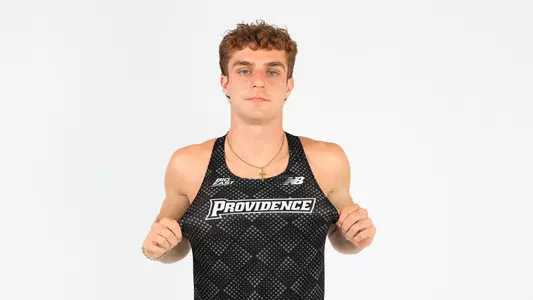 Ryan LoCicero pulling on his jersey to show the Providence logo during a photo shoot