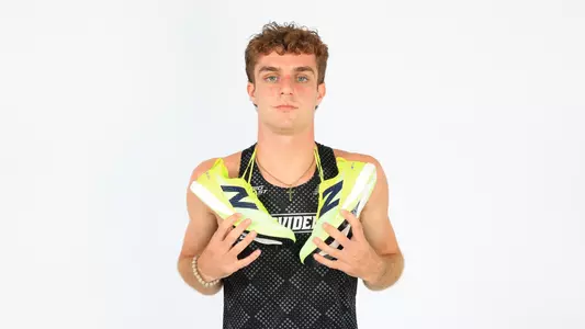 Ryan LoCicero posing with his spikes hanging around his shoulders during a photo shoot
