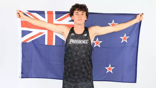 Elliott Pugh holding up the New Zealand flag during a photo shoot 