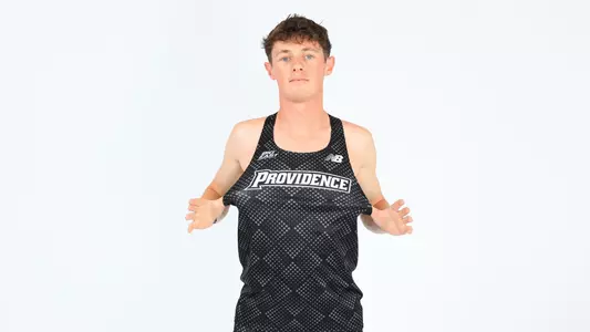Jack Small pulling on his jersey showing the Providence logo during a photo shoot